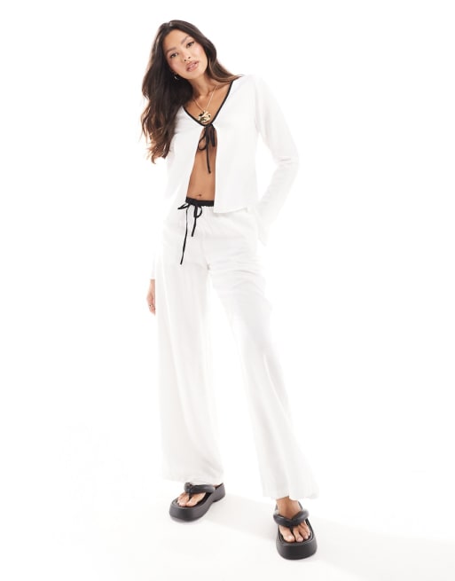 Conjunto playero blanco de pantalones y camisa con lazada delantera y ribete en contraste de lino de Kaiia