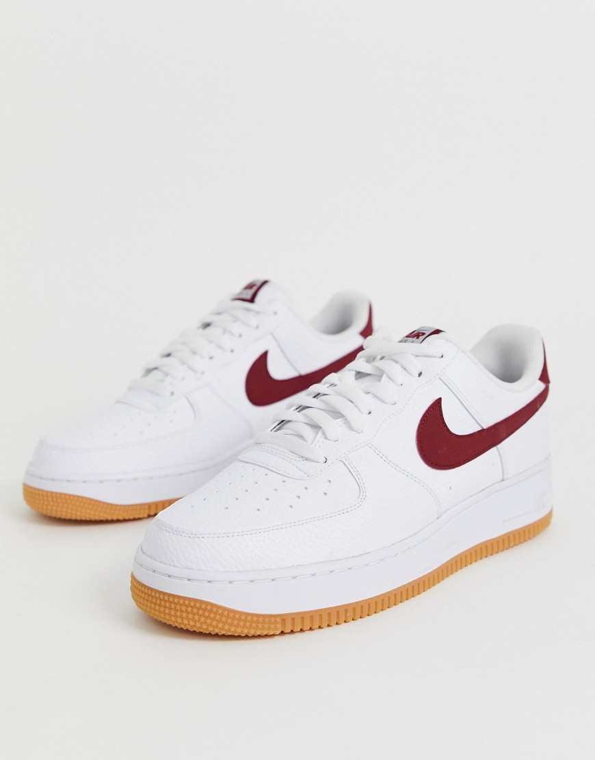 Nike Air Force 1 trainers with red swoosh and gum sole