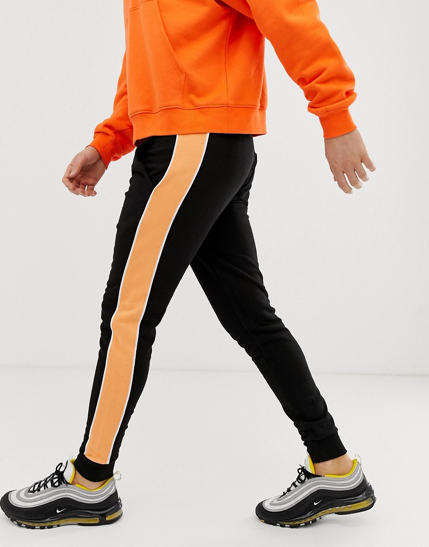 ASOS DESIGN skinny joggers in black with orange side stripe