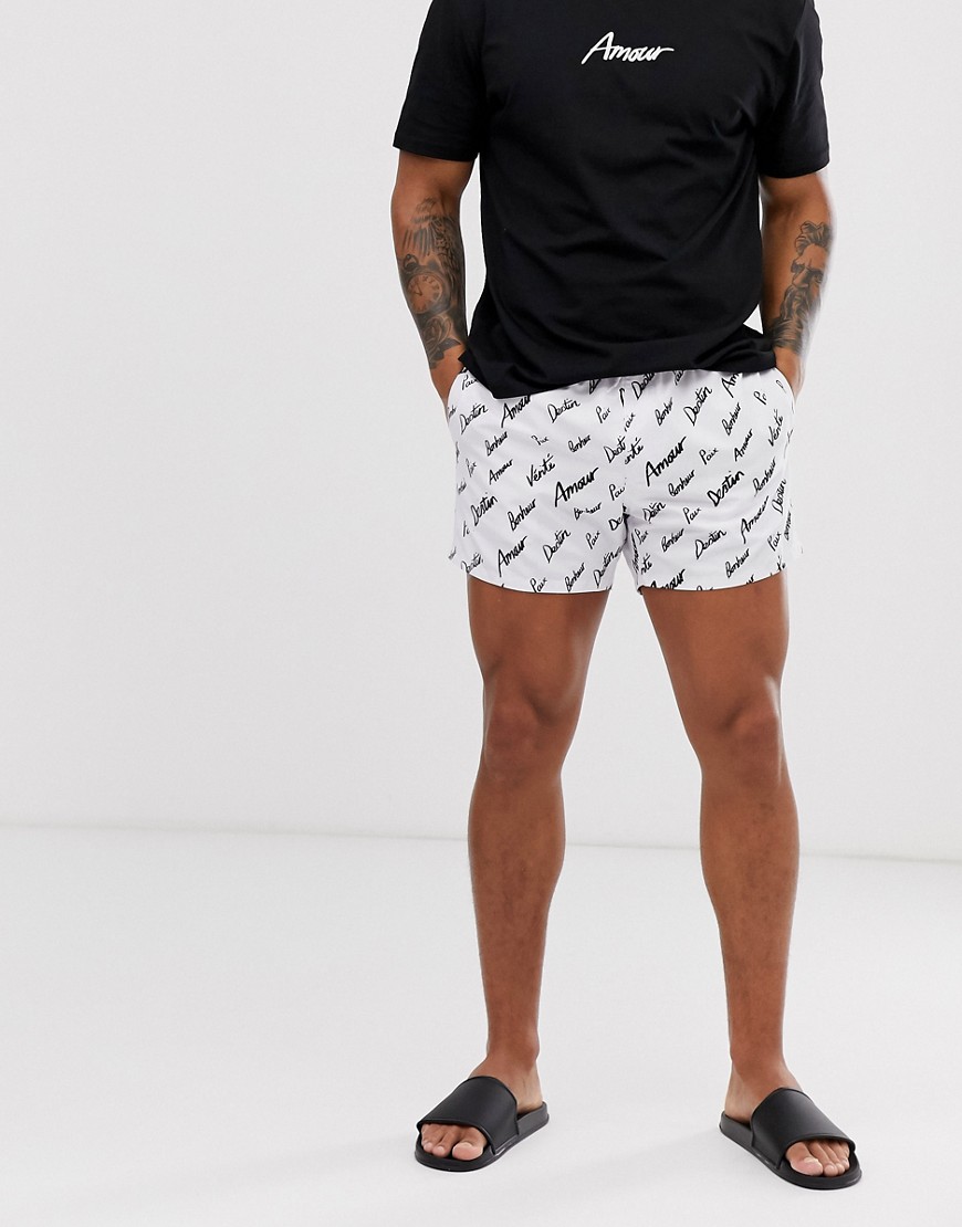 ASOS DESIGN co-ord swim shorts in white with all over slogan print short length
