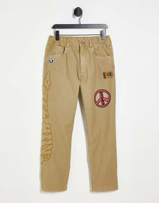 Aape By A Bathing Ape – Chinohose in Beige mit Peace-Detail