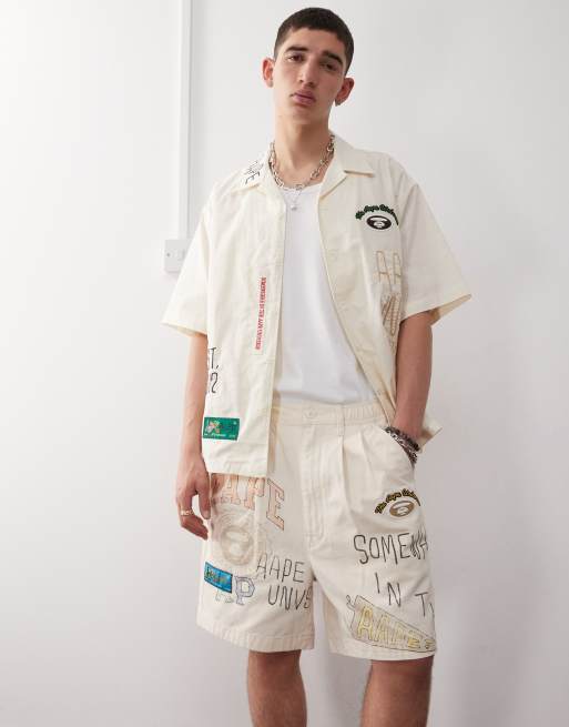 Aape by A Bathing Ape - Pantaloncini beige con logo multicolore stile college