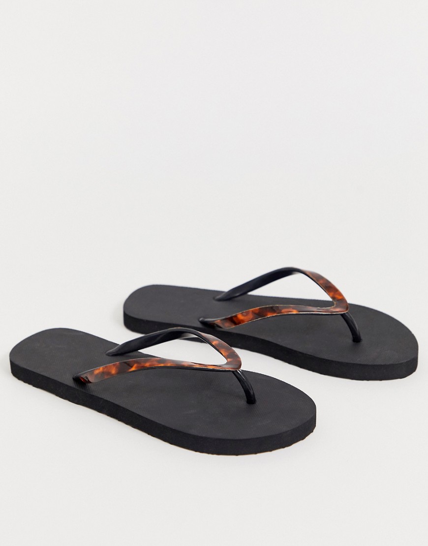 Accessorize black flip flops with tortoise effect straps