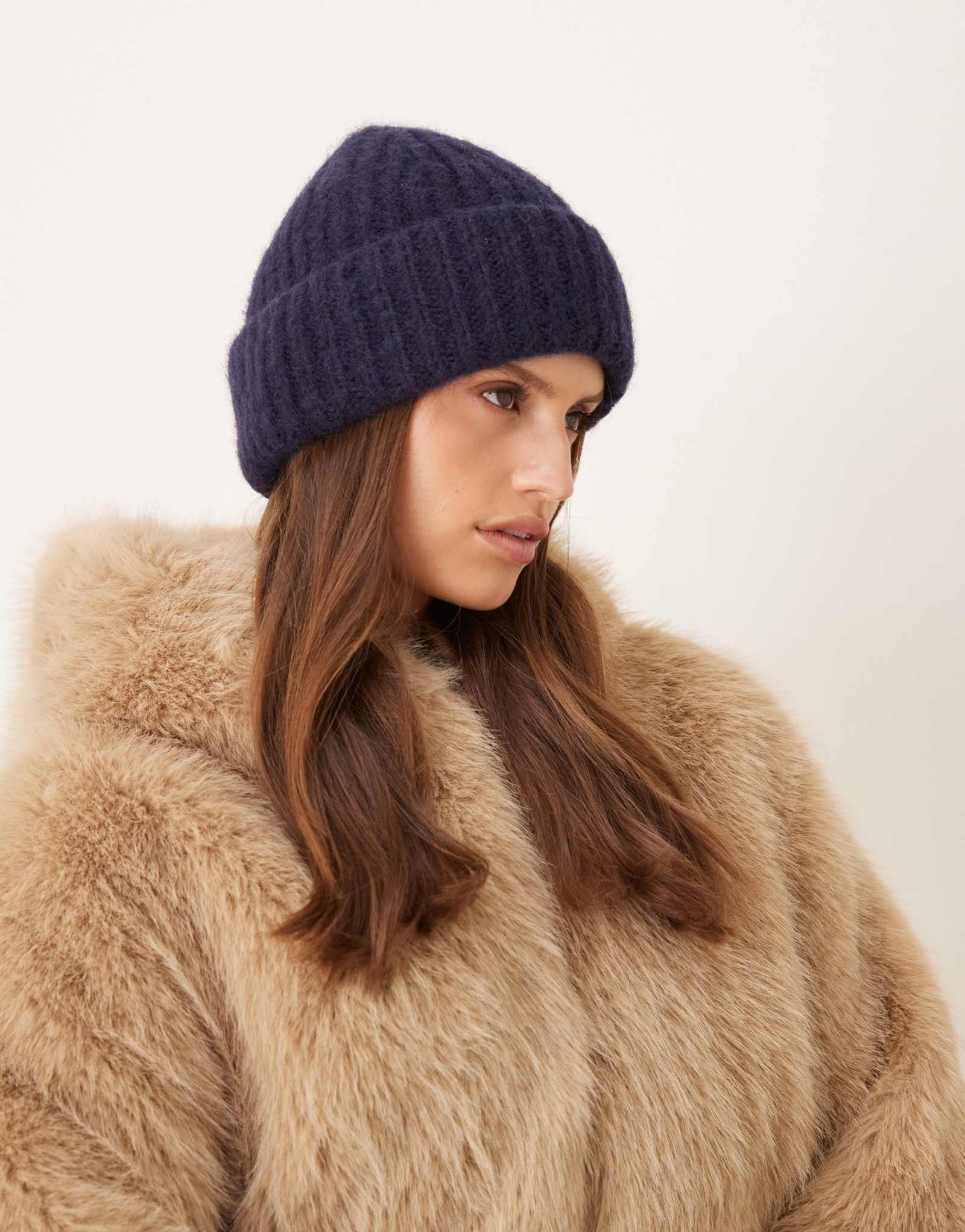 Дополните аксессуарами пушистую шапочку темно-синего цвета