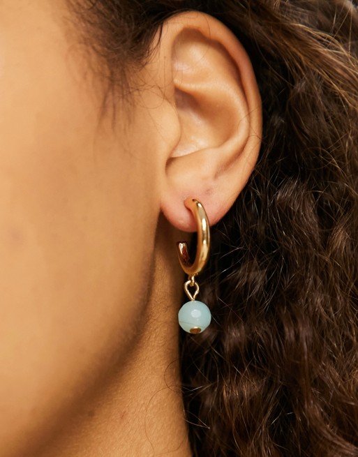 Accessorize hoop earrings with blue drop in gold