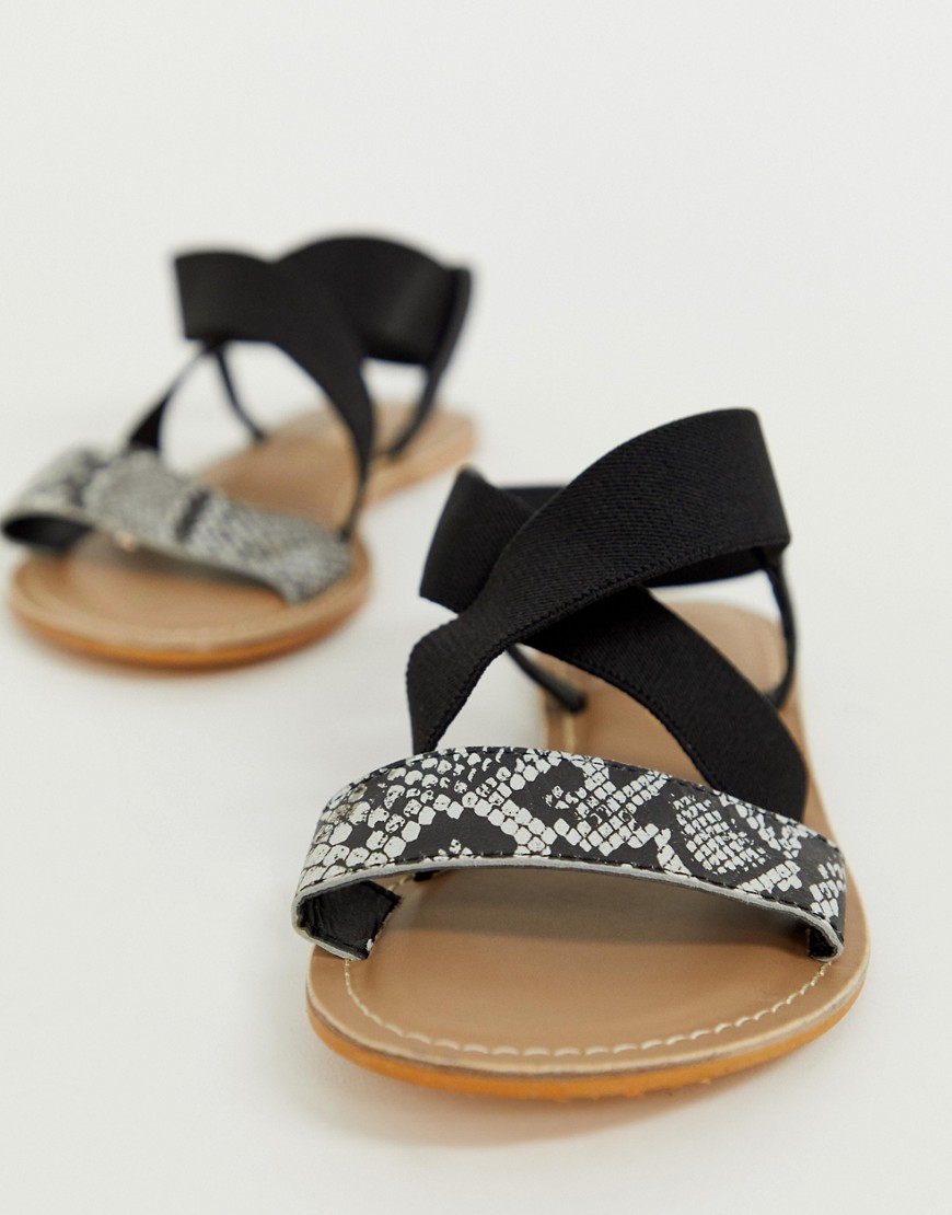 Accessorize – Ormskinnsmönstrade platta sandaler med elastiskt korsade remmar-Flerfärgad
