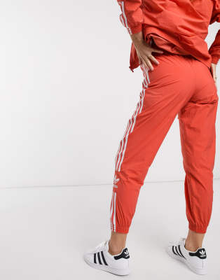 adidas originals adicolor locked up logo track pants in coral