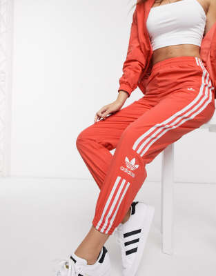 adidas originals adicolor locked up logo track pants in coral