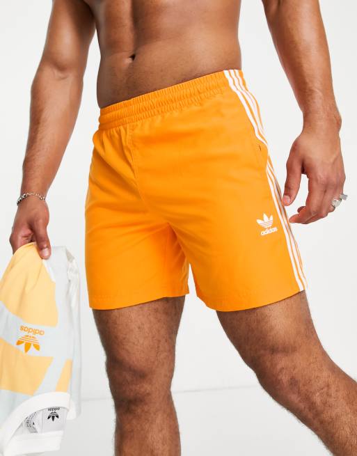 adidas Originals – adicolor – Pomarańczowe szorty kąpielowe z trzema paskami