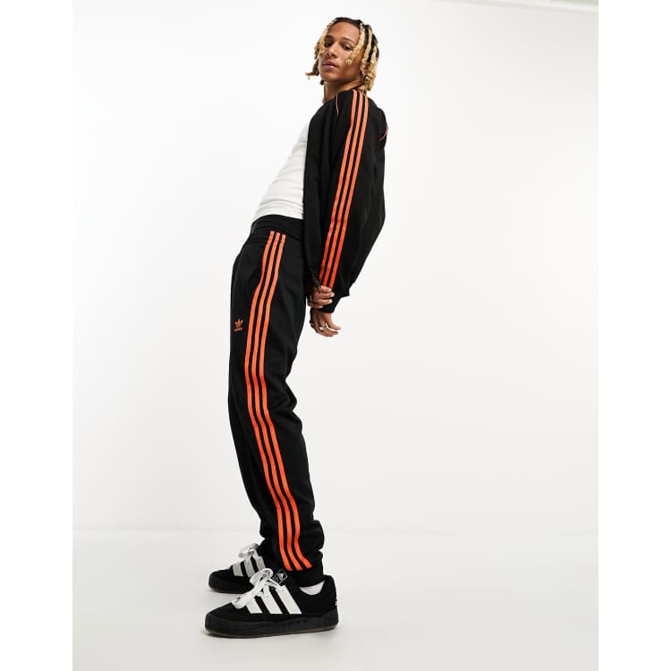 Black adidas tracksuit orange stripes sales