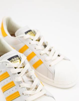 white adidas with yellow stripes