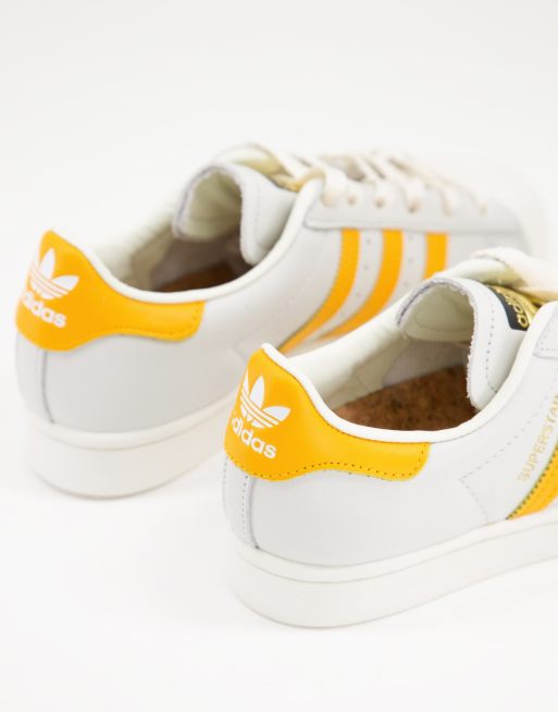 White adidas with store yellow stripes