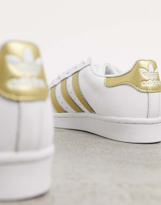 adidas Originals Superstar trainers in white with gold detailing