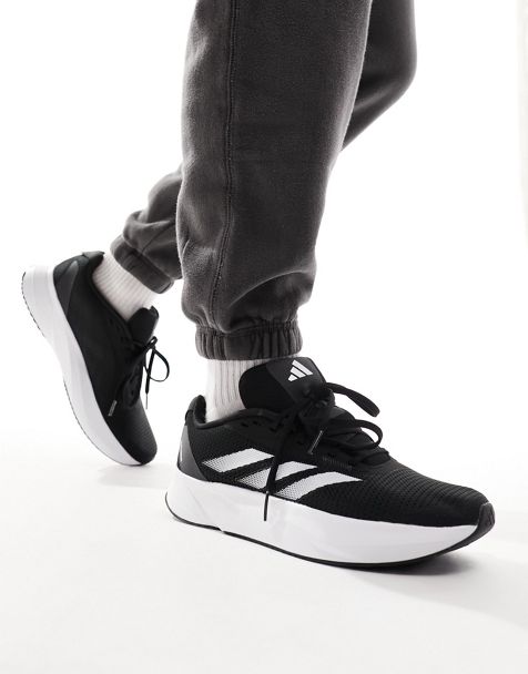 Tenue: Top court noir, Pantalon de jogging gris, Chaussures de sport  blanches et noires, Pochette en cuir noire