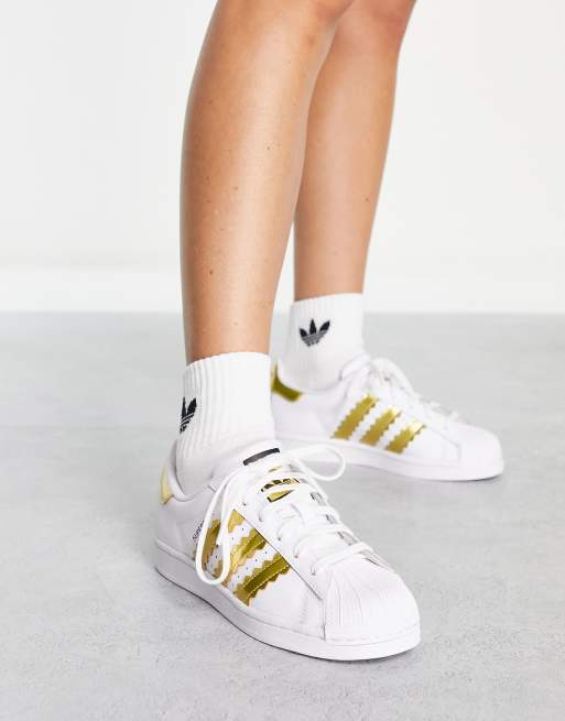 Adidas white shoes store with gold stripes