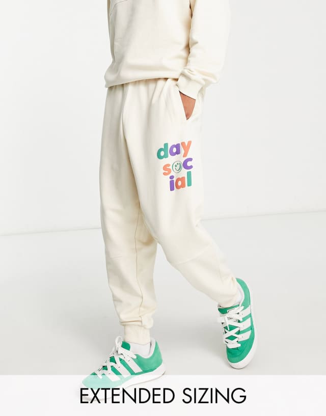 ASOS Daysocial relaxed sweatpants with multi logo prints and seam detailing in ecru - part of a set