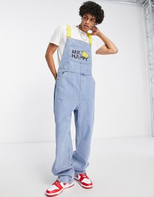 ASOS DESIGN baggy dungaree in mid wash with Mr Happy logo and contrast straps