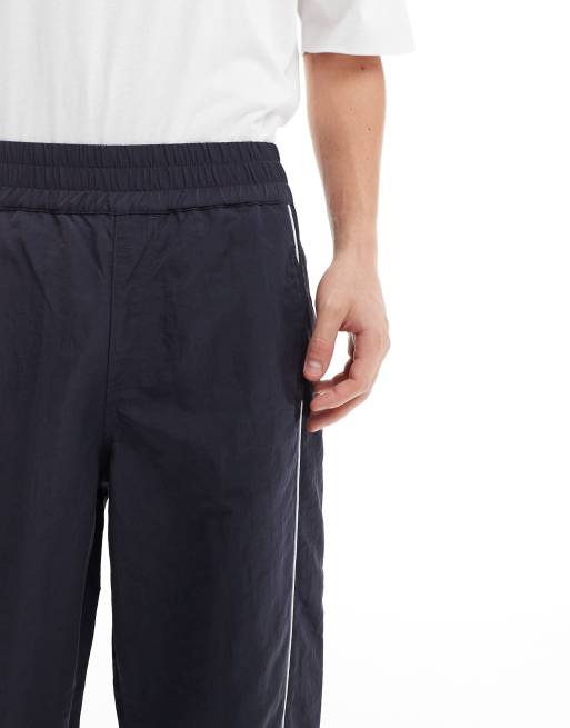 ASOS DESIGN baggy nylon track pants in navy with white piping