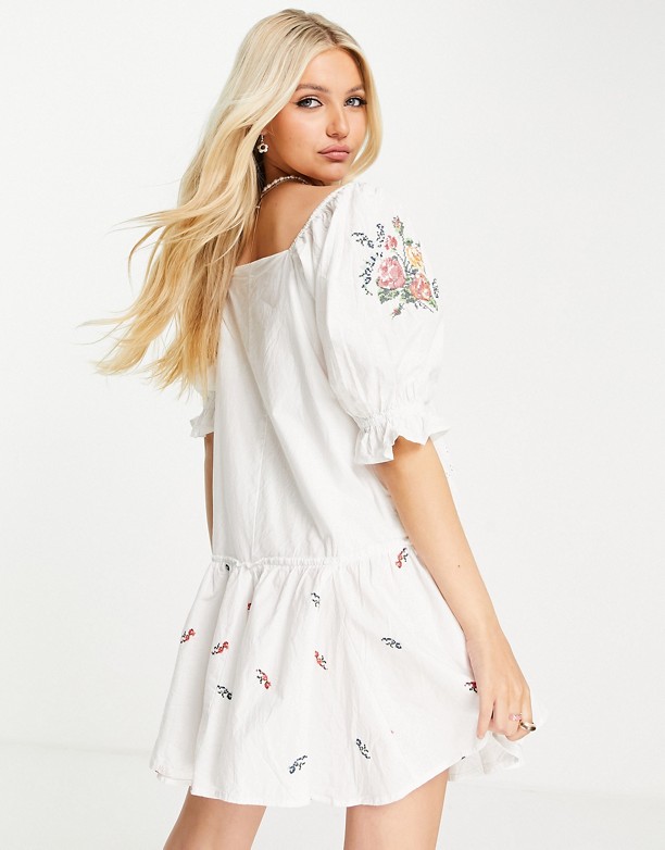  Modny ASOS DESIGN – Biała luźna bawełniana sukienka mini z haftowanym wzorem, koronkowym wykończeniem i baskinką Biały