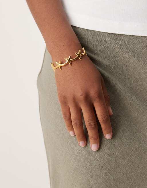 ASOS DESIGN - Bracciale rigido in acciaio inossidabile resistente all'acqua dorato con dettagli piccoli a forma di stelle marine
