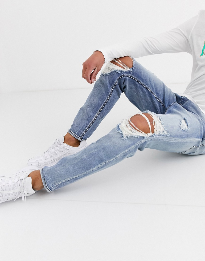 ASOS DESIGN carrot fit jeans in vintage light wash with heavy rips-Blue
