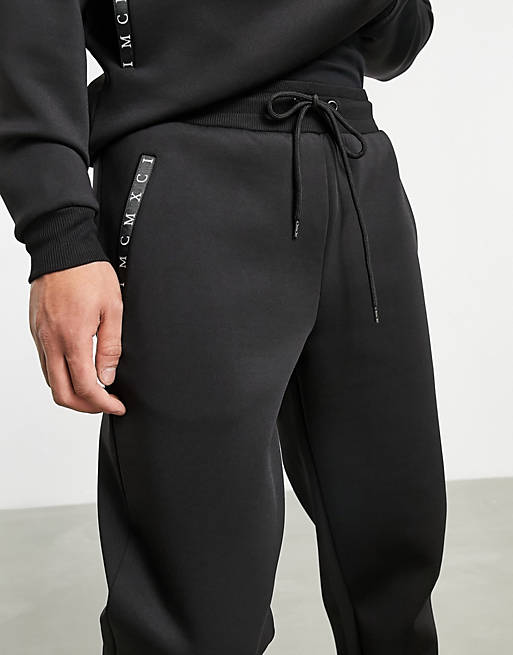 Tracksuits co-ord tapered joggers in black scuba with Roman numerals printed zips 