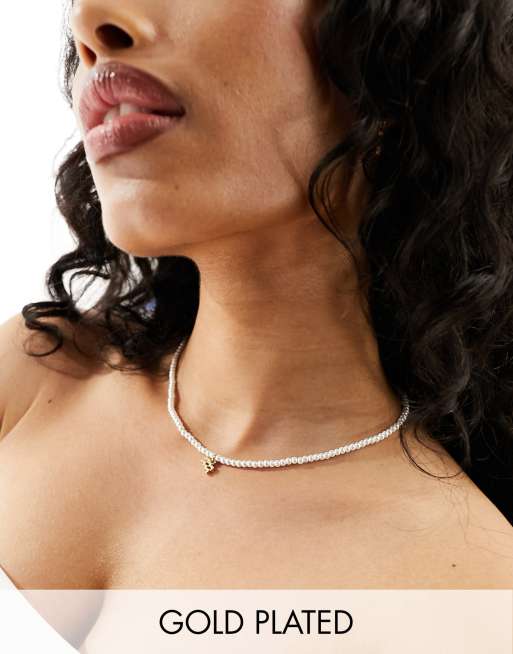 ASOS DESIGN - Collier de perles fantaisie en verre en plaqué or 14 carats avec signe astrologique Verseau et pochette cadeau