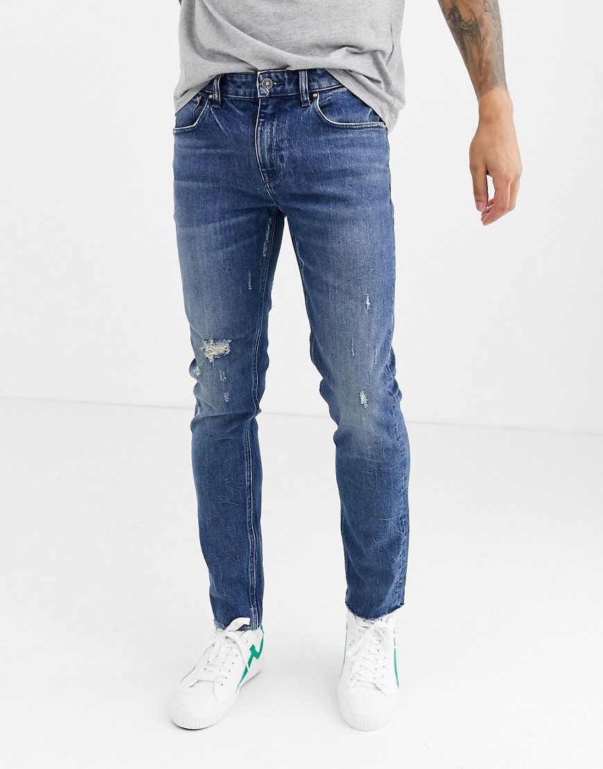 ASOS DESIGN Cone Mill Denim skinny 'American classic' jeans in mid wash blue with abrasions and raw hem