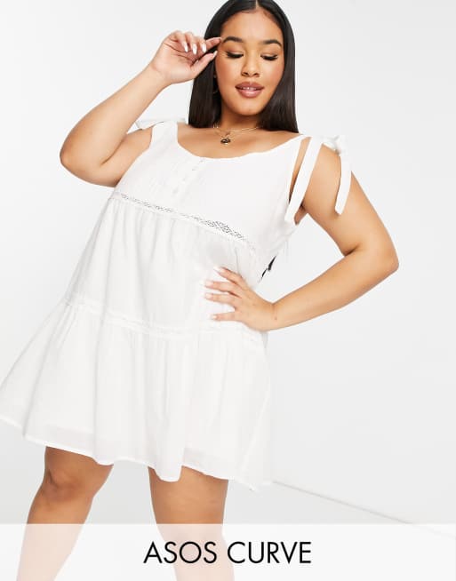 ASOS DESIGN Curve - Prendisole corto bianco stile grembiule, con inserto in pizzo e spalline annodabili
