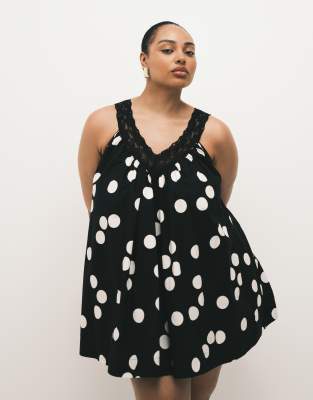 ASOS DESIGN Curve - Sommerliches Mini-Hängerkleid aus Popeline in Schwarz-Weiß gepunktet mit V-Ausschnitt und Spitzen-Ov...