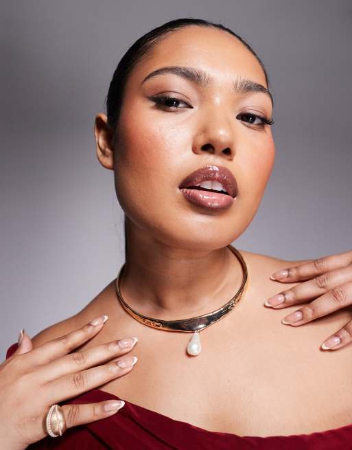 A plus-size, gold, sculptural choker with a pearl pendant