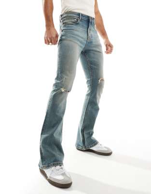 flared jeans with knee rips in tinted vintage blue