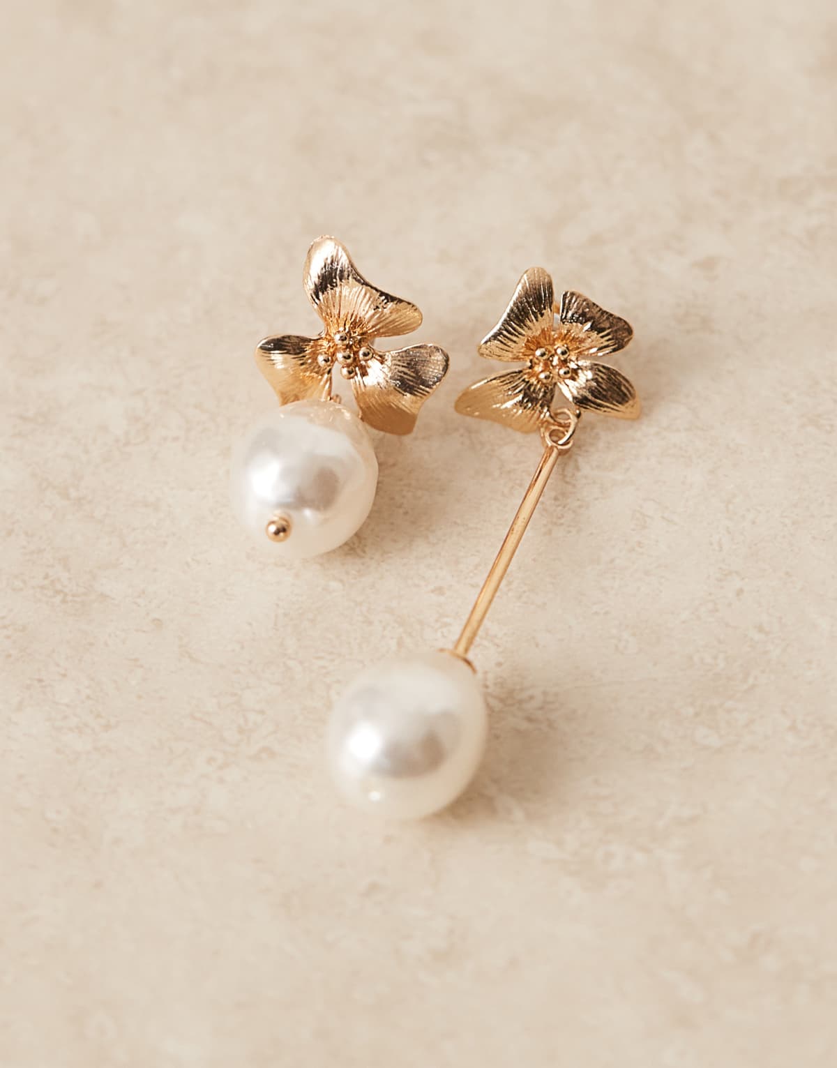 ASOS DESIGN flower stud earrings with asymetric pearl drop details in gold tone