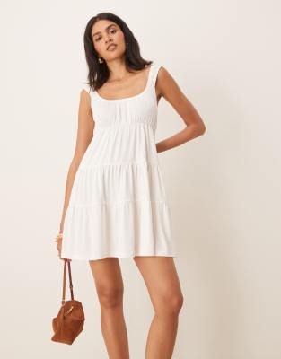 ASOS DESIGN - Gestuftes, schwingendes Babydoll-Minikleid in Elfenbeinweiß