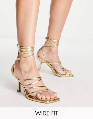 ASOS DESIGN - Hiccup - Riemchensandalen in weiter Passform mit Beinschnürung und mittelhohem Absatz in Gold-Goldfarben