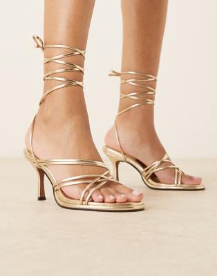 ASOS DESIGN - Hoola - Riemchensandaletten in Gold mit Beinschnürung und mittelhohem Absatz-Goldfarben