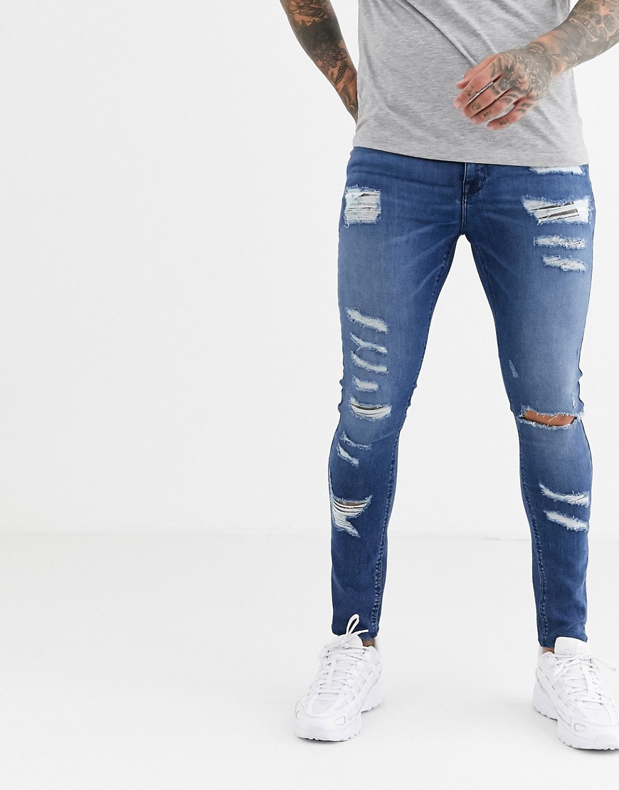 ASOS DESIGN - Jeans effetto spray in denim power stretch blu medio slavato con strappi vistosi
