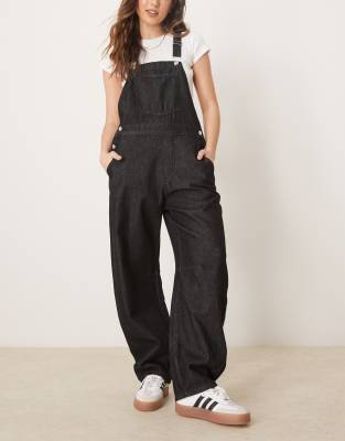 ASOS DESIGN - Jeans-Latzhose in Schwarz mit abgerundetem Beinschnitt