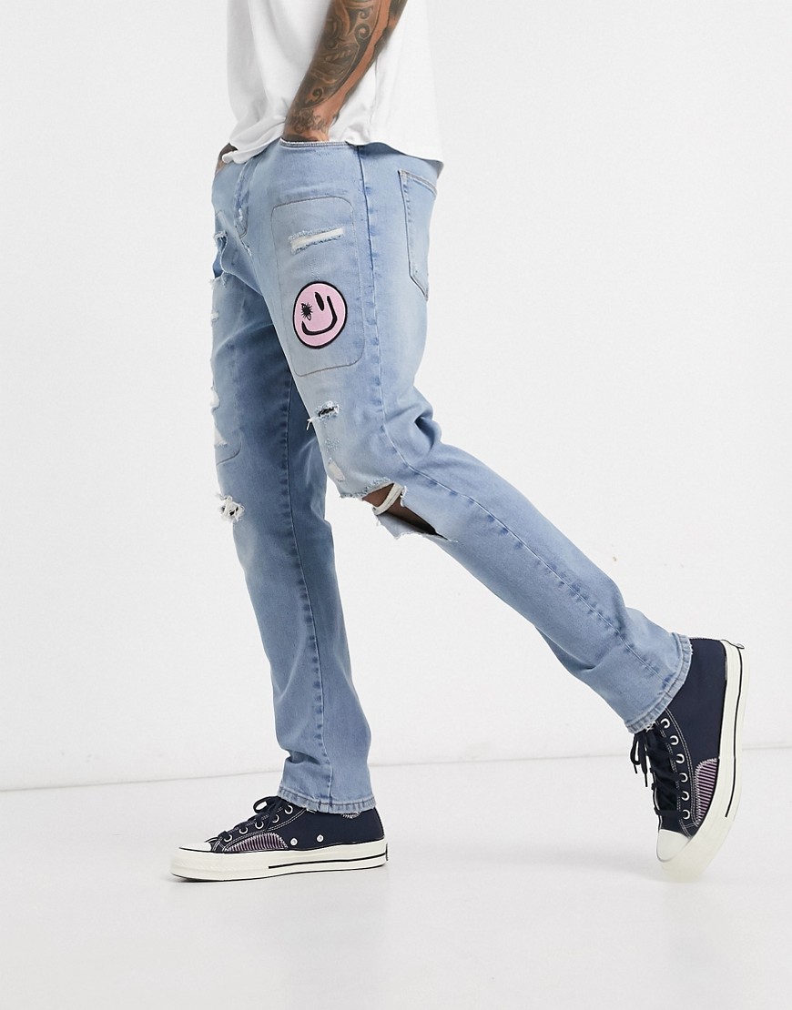 ASOS DESIGN - Jeans lavaggio chiaro blu con cavallo basso, strappi e abrasioni vistosi e toppe