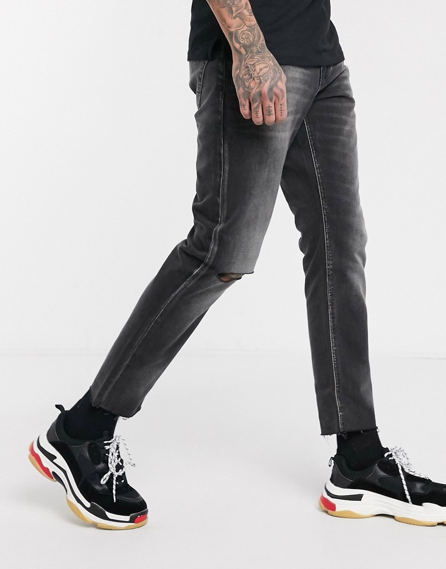 ASOS DESIGN - Jeans slim rigidi corti nero slavato con strappi alle ginocchia e fondo grezzo