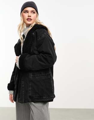 ASOS DESIGN - Lang geschnittene Jeansjacke in verwaschenem Schwarz mit Teddyfutter