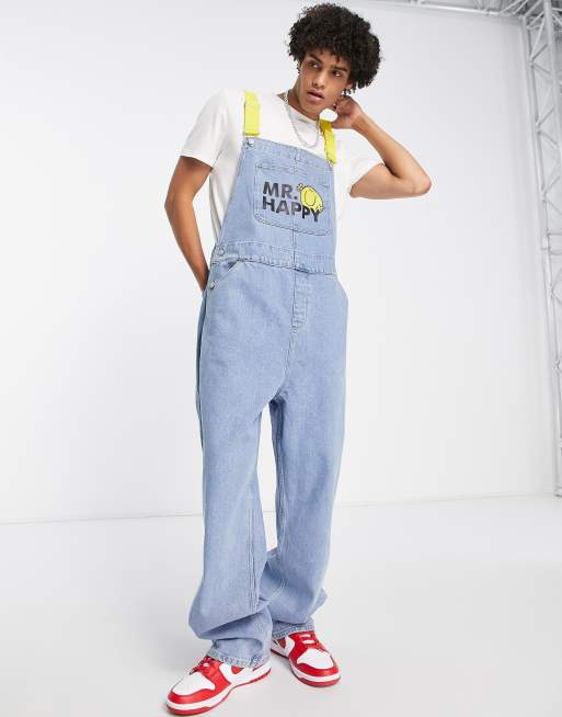 ASOS DESIGN – Mellanblå baggy hängselbyxor med Mr Happy-logga och kontrasterande hängslen