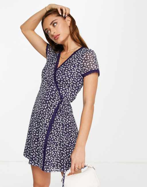 ASOS DESIGN – Mini-Wickelkleid aus Netzstoff mit Spitzenbesatz in Marineblau mit Gänseblümchen-Print