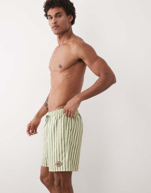 ASOS DESIGN – Mittellange, gestreifte Badeshorts in Gelb und Grün mit gesticktem Aufnäher, 5 von 5