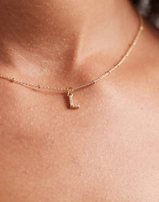 ASOS DESIGN – Naszyjnik z kuleczkami w kolorze złota z zawieszką z literą L wysadzaną cyrkoniami w torebce prezentowej