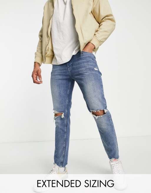 ASOS DESIGN – Niebieskie jeansy o obcisłym kroju z przetarciami na kolanach i surowym wykończeniem 
