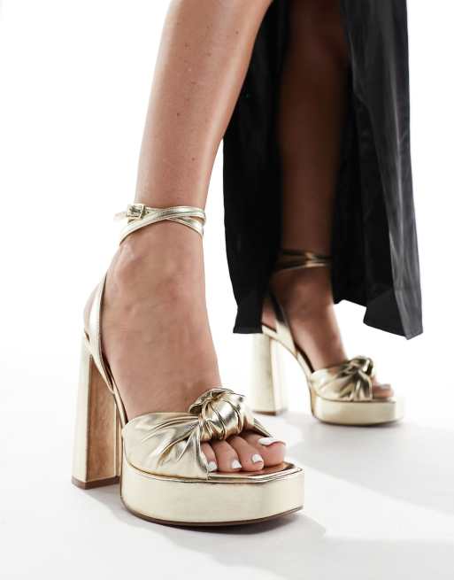 ASOS DESIGN – Nikita – Sandaletten in Gold mit Zierknoten, Plateausohle und Blockabsatz