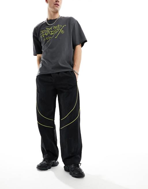 ASOS DESIGN paneled piping track pants in black and yellow sheen