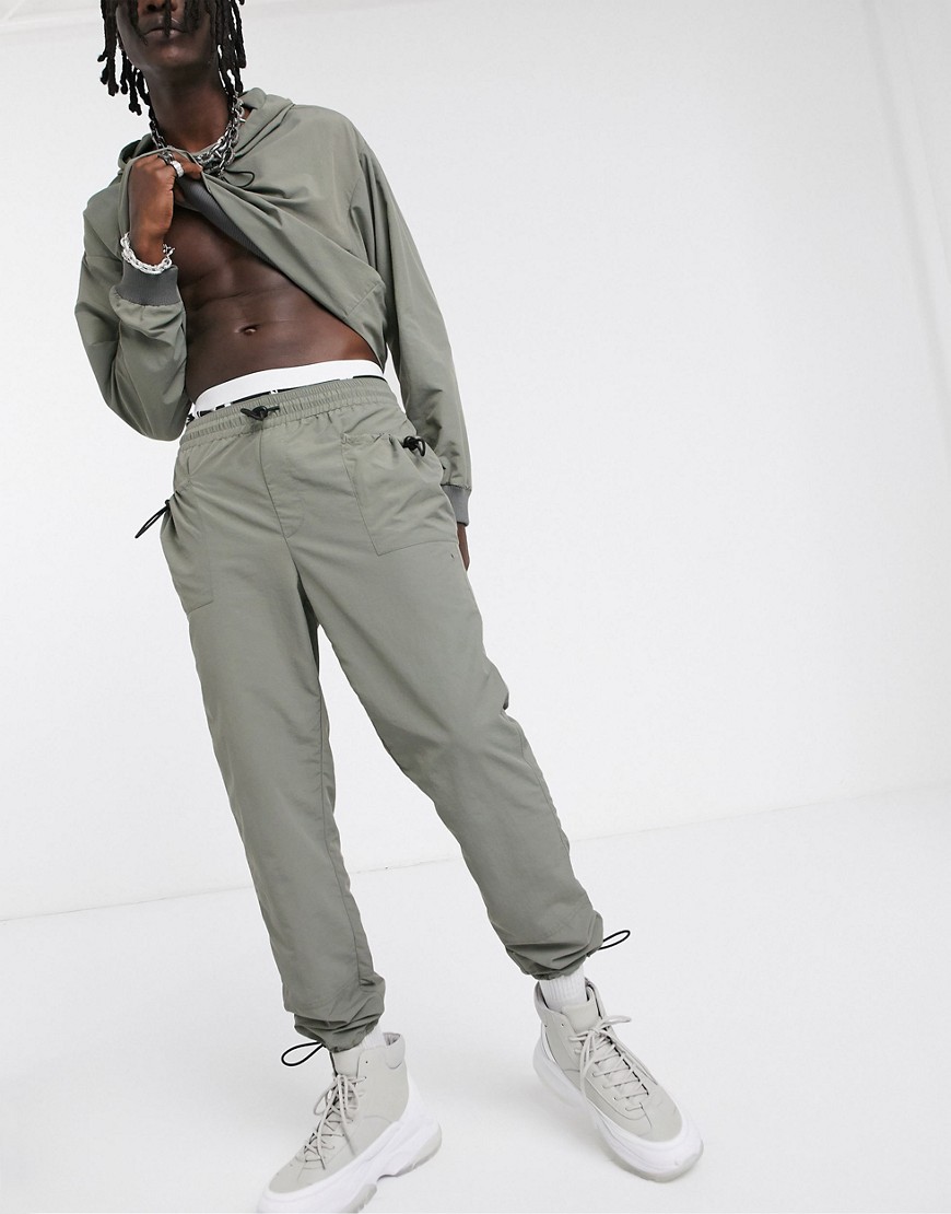 ASOS DESIGN - Pantaloni affusolati in nylon con fermacorda su tasche e fondo elasticizzato in coordinato-Verde