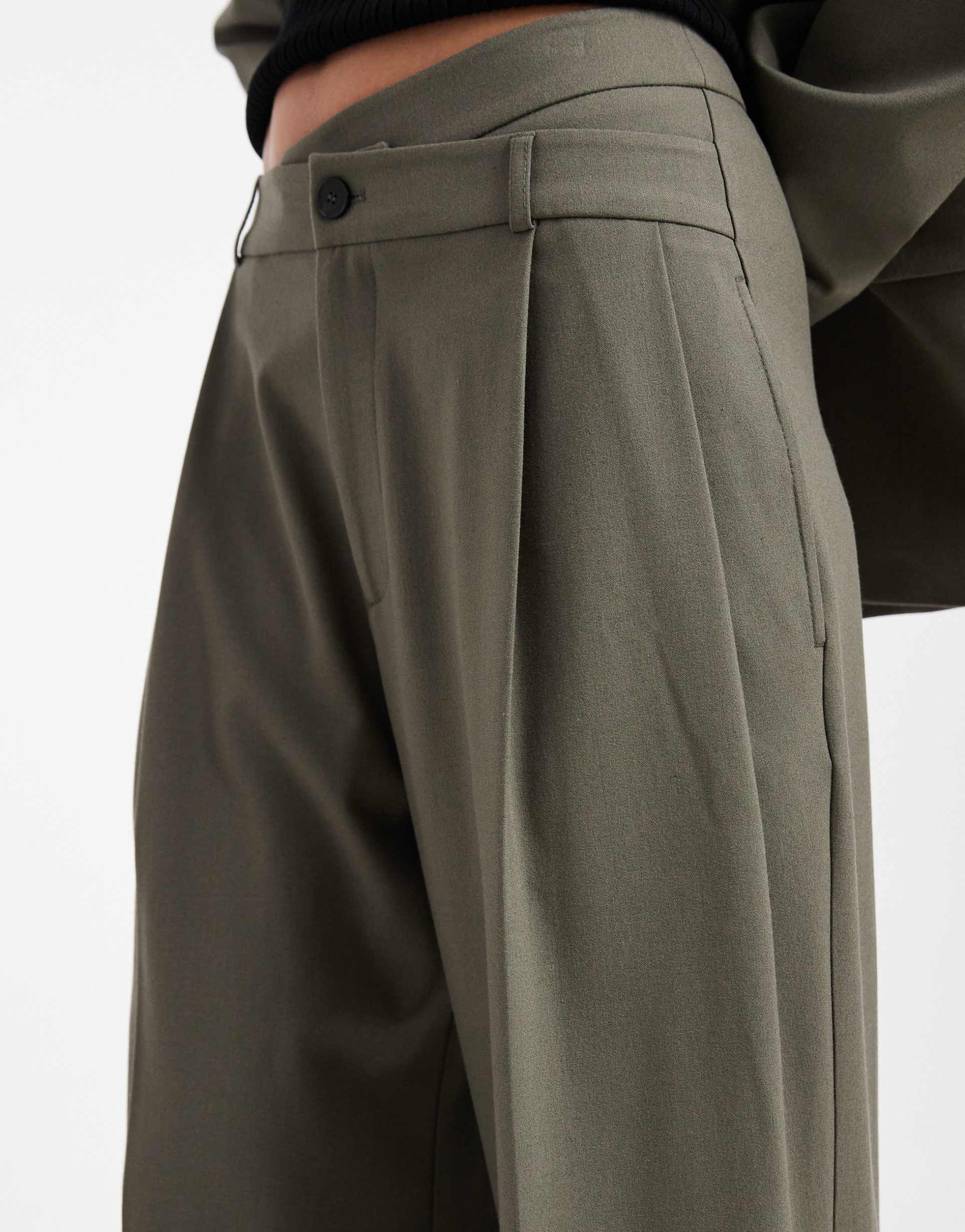 ASOS DESIGN: Pantaloni sartoriali a vita bassa in tonalità di oliva con ampio fondo e fascia asimmetrica coordinata